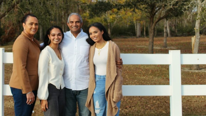 2 women and man standing beside white wooden fence during daytime